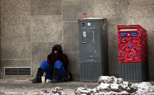 WEATHER STANDUP - Frigid temperatures clinch Winnipegers. This street person sits on Portage Ave near the MTS Centre. BORIS MINKEVICH / WINNIPEG FREE PRESS January 14, 2016