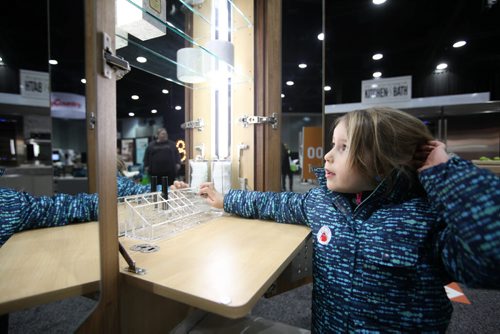 Five-year-old Ellie Chapko checks her reflection in a dressing mirror at the GreenSlade booth at the Winnipeg Renovation Show Friday afternoon with their grandfather.  The show runs throughout the weekend at RBC Convention Centre.   Standup Jan 15, 2016 Ruth Bonneville / Winnipeg Free Press