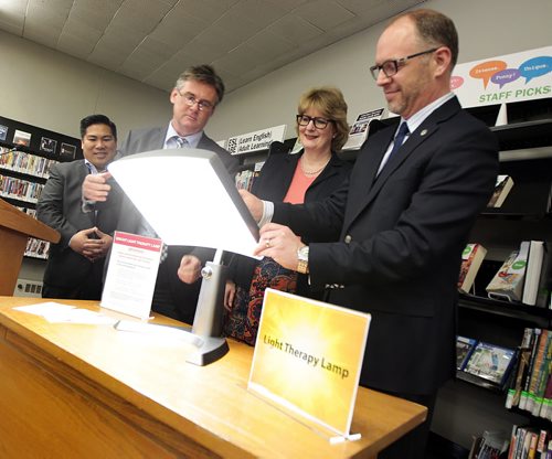 Blue Monday - Left to right, Counsillor Mike Pagtakhan, Rick Walker of Library Services, Tara Brousseau Snider, Executive Director of Mood Disorders Association of Manitoba abd City Coucillor Scot Gillingham turn on a light therapy lamp at the St James-Assinaboia Library Monday launching a new initiative to help combat Seasonal Affective Disorder. See release.  January 18, 2016 - (Phil Hossack / Winnipeg Free Press)