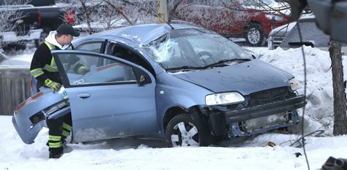 A tow truck operator prepares to remove a car that rolled on to the boulevard along Pandora Ave. West near Heartstone Dr. Wednesday morning  that sent the three occupants including two children to the hospital. Wayne Glowacki / Winnipeg Free Press Jan. 20 2016