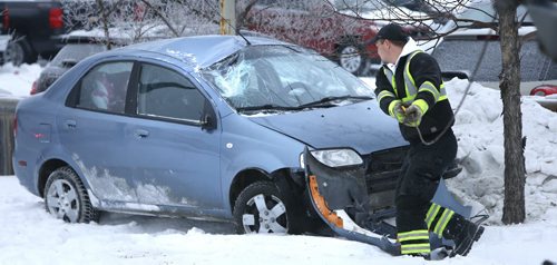 A tow truck operator prepares to remove a car that rolled on to the boulevard along Pandora Ave. West near Heartstone Dr. Wednesday morning that sent the three occupants including two children to the hospital. Wayne Glowacki / Winnipeg Free Press Jan. 20 2016