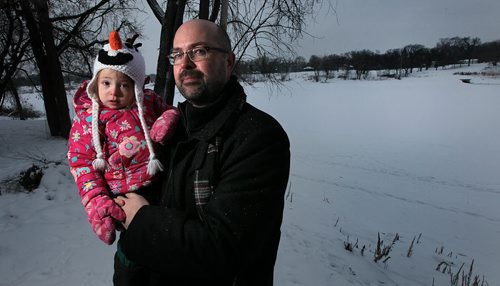 Craig Tulloch and his daughter Mamie pose behind their Glenwood Cres home across from a storm sewer outlet near St Johns Park where raw sewage has been leaking into the Red River. Tulloch said the smell was so bad from the leak they thought it was their daughters diaper. Aldo Santin story.  January 20, 2016 - (Phil Hossack / Winnipeg Free Press)
