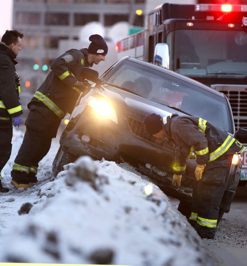 Winnipeg Fire Fighters speak to the occupant in a car hung up on a snow bank on Donald Street near Wardlaw Avenue Friday morning. Wayne Glowacki / Winnipeg Free Press Jan. 22 2016