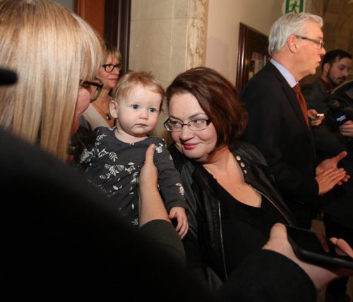 Fort Rouge MLA Jennifer Howard leans into her 8-month-old daughter, Georgia, held by Howard's wife, Tara Peel, while Premier Selinger talks to the media about Howard not seeking re-election and  departure from the NDP party at press conference at the Leg Wednesday afternoon.   Jan 27, 2016 Ruth Bonneville / Winnipeg Free Press