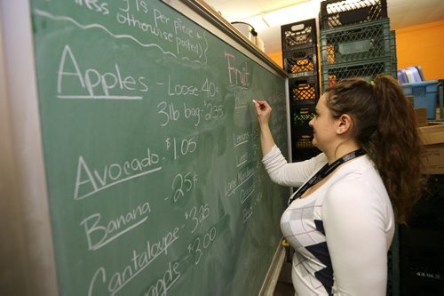 Stephanie Behl writes fruit prices on a chalk board at Agape Table's low-cost grocery at 175 Colony St., near Broadway and Osborne Street on Jan. 27, 2016. Agape Table offers choices of good nutritious food for at-cost (or below) prices, so community members can have the opportunity to eat healthy. The Community Nutrition Centre offers a variety of emergency and low-cost meal and grocery programs to assist low-income residents of Winnipeg. Photo by Jason Halstead/Winnipeg Free Press RE: Social Page