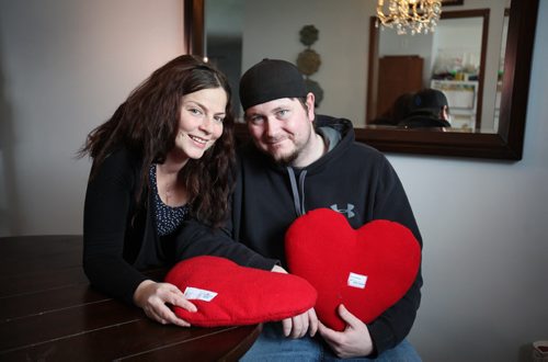 Sherene Wright and Russell MacDougall, both heart transplant recipients, cuddle together at their home holding heart-shaped pillows made by volunteers for St. Boniface Hospital heart surgery patients.  Portraits taken for Valentine's Day story on how heart patient couple met in the cardiac intensive care unit and now are getting married in September.    See Kevin Rollason  | Reporter February 11, 2016 Ruth Bonneville / Winnipeg Free Press