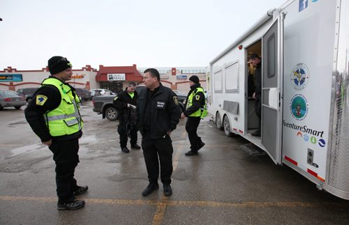 Ruth Bonneville / Winnipeg Free Press Sargent Randy Antonio, coordinator for the Wpg Police Ground Search and Rescue (centre) talks to one of his crew that were out searching  with him along the banks of the Red River north of the Perimeter off Henderson Hwy.Thursday at dispatch trailer in the parking lot of McIvor Mall. Feb 18, 2016