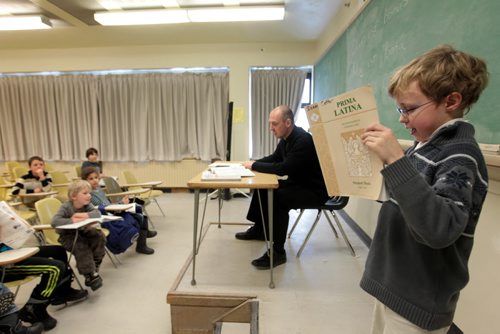 RUTH BONNEVILLE / WINNIPEG FREE PRESS Young homeschooled Catholic students are enthusiastic as they read aloud, answer questions and learn new words in their Latin class at St. Paul's College Friday.  Rev. Jeffrey Burwell, Director of the Jesuit Centre for Catholic Studies teaches Latin and music courses at the college to broaden their understanding of their faith and other languages.  See Faith story by Brenda Suderman.  Names: Isaac Cotter volunteers to read aloud a prayer in Latin to the class.   February 19, 2016