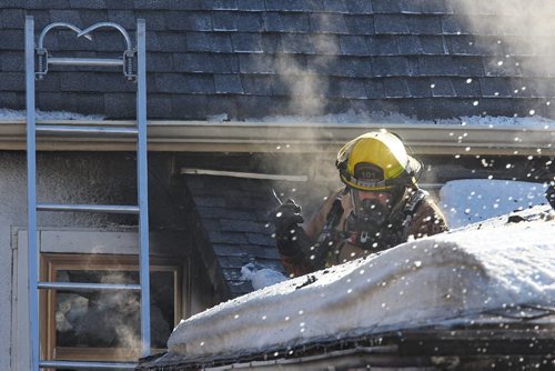 MIKE DEAL / WINNIPEG FREE PRESS A firefighter battles a garage fire at a house in the 500 block of Beverly Street at Sargent Avenue, two people were being examined by emergency paramedics at the scene for possible smoke inhalation. The fire damaged the house as well as destroyed the garage.   160302 March 02, 2016
