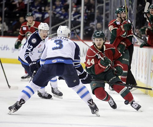 PHIL HOSSACK / WINNIPEG FREE PRESS Iowa Wild #44 Christoph Bertschy flips the puck over Manitoba Moose #3 Jan Kostalek's stick and prepares to fight his way into the Moose end Wednesday at the MTS Center.  March 9, 2016