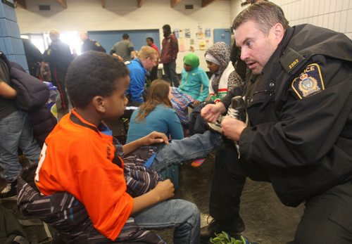 JOE BRYKSA / WINNIPEG FREE PRESS  About 120 kids joined the Winnipeg Police, Cadets at Pioneer Arena (799 Logan Avenue) for a afternoon skate called Skates and Badges -  The learn-to-skate event  brought about 120 children who enjoyed drinks and pizza after the event- Said Osman from Pinkham Elementary School gets a hand putting on his skates from Winnipeg Police Service Const Kevin Chinchilla, March 11, 2016.(Standup Photo)