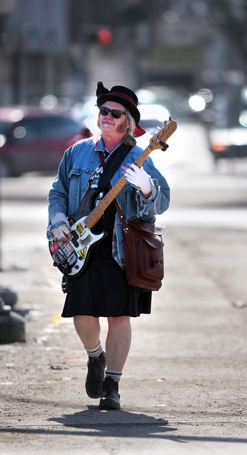 PHIL HOSSACK / WINNIPEG FREE PRESS Sunny Day........Local Bassist Patrick Boggs makes his way north along main street Monday afternoon. Not an uncommon sight in the Woseley area, Patrick said the beautiful warm sunny day inspired him to see how far n orth he could walk while picking bass lines to his guitar plugged into his ear buds.  March 14, 2016