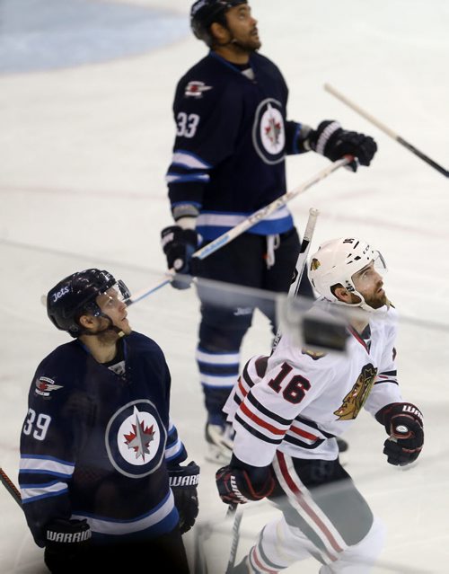 TREVOR HAGAN / WINNIPEG FREE PRESS Winnipeg Jets' Toby Enstrom (39), Dustin Byfuglien (33) and Chicago Blackhawks' Andrew Ladd (16) look up at the replay after Ladd scored during third period NHL hockey action, Friday, March 18, 2016.