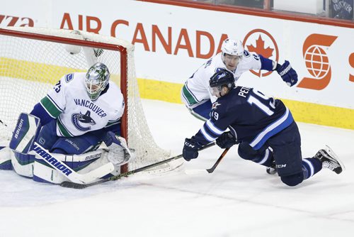 JOHN WOODS / WINNIPEG FREE PRESS Winnipeg Jets' Nic Petan (19) attempts the wraparound on Vancouver Canucks goaltender Jacob Markstrom (25) as Alexandre Burrows (14) defends during first period NHL action in Winnipeg on Tuesday, March 22, 2016.