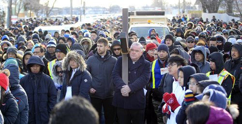 PHIL HOSSACK / WINNIPEG FREE PRESS Archbishop of Winnipeg Most Reverend Richard Gagnon symbolically bearing a large wooden cross leads a procession of a thousand or more faithfull as they leave St Peter's Church on Keewatin street Friday morning to follow the "Stations of the Cross" as Easter weekend begins for Christians world wide. See Scott Billeck story. March 25, 2016