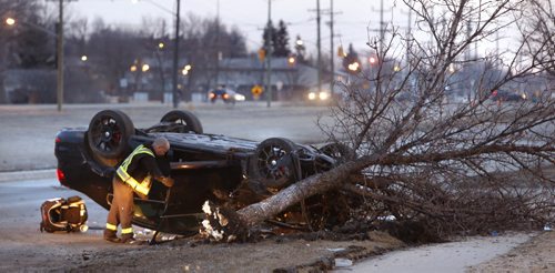 WAYNE GLOWACKI / WINNIPEG FREE PRESS   A tow truck operator prepares to remove an overturned car on Gateway Rd. just north of Burnett Ave.¤Tuesday morning.¤ There was only one person in the vehicle at the time of the crash and is listed in stable condition.  March 29 2016