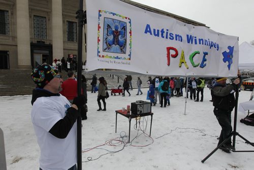 RUTH BONNEVILLE / WINNIPEG FREE PRESS  Autism Manitoba Founder Mike Wilwand raises sign in front of the Legislative Building after walk celebrating World Autism Awareness Day with families and friends with autistic children Saturday.  Also taking place at the same time on the steps of the Leg is an anti-CFS rally takes place using a loudspeaker to announce their claims against CFS.    April 02, 2016