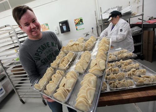 PHIL HOSSACK / WINNIPEG FREE PRESS Perogy Planet's Rob Naleway shows off a tray of perogy ready to for the display shelf. Lydia Rabada fills mor pacjages behind him.  Dave Sanderson story. - April 5, 2016