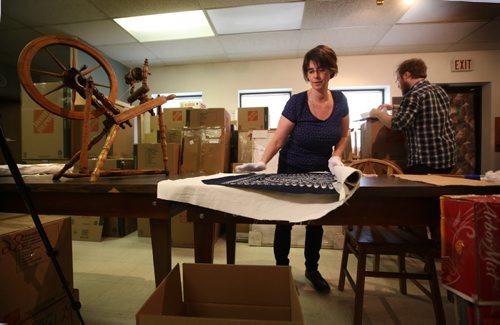 RUTH BONNEVILLE / WINNIPEG FREE PRESS  Andrea Reichert, curator of the Manitoba Crafts Museum and Library on Kennedy is packing up and moving to a new location near the Exchange District.  Reichert rolls up a large chinese Batik while curatorial assistant, Eric Napier Strong packs articles into boxes Wednesday.   See Alan Small's story on fundraising social being held this Saturday for the centre.    April 06, 2016