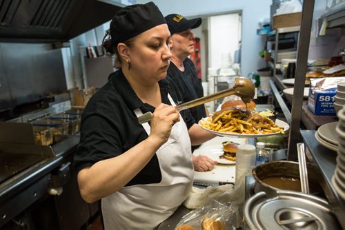 MIKE DEAL / WINNIPEG FREE PRESS Sunday This City piece on Pete's Place, a home-style restaurant celebrating its 15th anniversary this year. Samantha and Peter Vlahos, the owners, worked at some of the finer greasy spoons in the city before opening their own joint in 2001. Cook Felicia puts the finishing touches on a lunch with fries by adding gravy. 160407 - Thursday, April 07, 2016