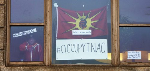 WAYNE GLOWACKI / WINNIPEG FREE PRESS  A protester peers out of the window of the Government of Canada's Aboriginal Affairs and Northern Development office Friday morning.   Protesters have been peacefully occupying the Winnipeg office for the past 24 hours in response to the suicide epidemic in Attiwaspikat and Pimicikamak. The protesters joined the #OccupyINAC campaign that originally began in Toronto on Wednesday.    April 15  2016