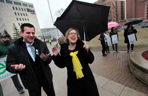 PHIL HOSSACK / WINNIPEG FREE PRESS Manitoba Green Party leader James Beddome and National Green Party leader Elizabeth May share a laugh despite the rain at a rally for a $15 minimum wage that gathered at the Univercity of Winnipeg Friday at noon before marching down Portage ave.  APRIL 15, 2016