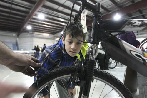 RUTH BONNEVILLE  Ten-year-old Hunter Wiebe, with the help of WRENCH volunteers, works on his new/used bike  that his mom bought for him at the City of Winnipeg annual unclaimed bike auction at East End Arena Saturday.Standup photo  April 16, 2016
