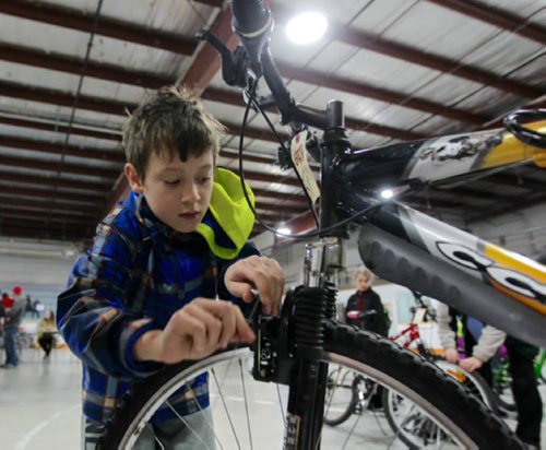 RUTH BONNEVILLE / WINNIPEG FREE PRESS  Ten-year-old Hunter Wiebe, with the help of WRENCH volunteers, works on his new/used bike  that his mom bought for him at the City of Winnipeg annual unclaimed bike auction at East End Arena Saturday.  Standup photo  April 16, 2016