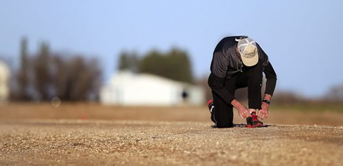 PHIL HOSSACK / WINNIPEG FREE PRESS On the eve of the provincial election, Brian Pallister stops to tie a shoelace as he runs the gravel road at his family's farmstead near Edwin Mb SW of Portage La Prairie Monday evening. It's been a personal tradition for him to visit the farm run the section to prepare for election day. April 18, 2016 - APRIL 15, 2016