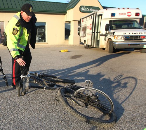 WAYNE GLOWACKI / WINNIPEG FREE PRESS   A Winnipeg Police officer removes a mangled bicycle Tuesday morning after a cyclist was killed in a hit and run on Nairn Ave. near Chester St. overnight.  Bill Redekop story  April 26 2016