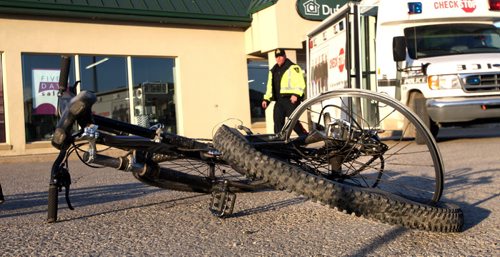 WAYNE GLOWACKI / WINNIPEG FREE PRESS   A Winnipeg Police officer prepares to removes a mangled bicycle Tuesday morning after a cyclist was killed in a hit and run on Nairn Ave. near Chester St. overnight.  Bill Redekop story  April 26 2016