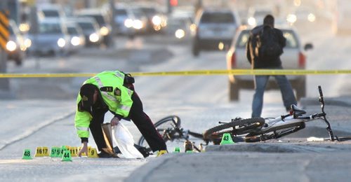 WAYNE GLOWACKI / WINNIPEG FREE PRESS   A Winnipeg Police officer collects evidence on Nairn Ave. near Chester St. Tuesday morning after a cyclist was struck by a vehicle over night.There were two bicycles at the scene, one at right on the sidewalk and a mangled bike on Nairn Ave. behind the officer.  Bill Redekop story  April 26 2016