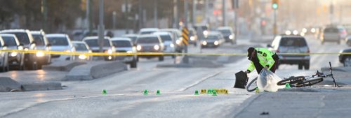 WAYNE GLOWACKI / WINNIPEG FREE PRESS   A Winnipeg Police officer  collects evidence on Nairn Ave. near Chester St. Tuesday morning after a cyclist was struck by a vehicle over night.There were two bicycles at the scene, one at right on the sidewalk and a mangled bike on Nairn Ave. behind the officer.  Bill Redekop story  April 26 2016