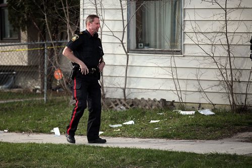 PHIL HOSSACK / WINNIPEG FREE PRESS A city police officer stands in front of 1887 Alexander ave  (littered with medical supply refuse from responders) where a man was stabbed Wednesday afternoon. See Alex Paul's story. April 27, 2016