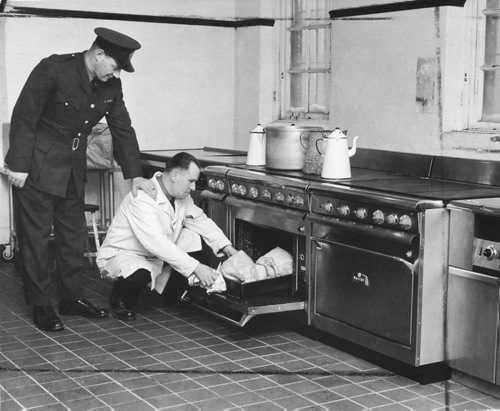 Headingley Jail, Dec 24, 1955.  Scanned from photograph.  Some of the $40,000 worth of new kitchen equipment being installed in Headingley jail.  Here shown is Christmas turkeys.  W.E Lawson, assistant superintendent, looks over the shoulder of W. Ewaskiw, one of the cooks.