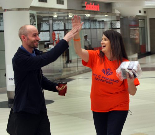 WAYNE GLOWACKI / WINNIPEG FREE PRESS   Steve Funk gets a high five from Yvette Deveau, she was among the over dozen people who took part in International Pay It Forward Day Thursday morning in the pedestrian concourse by the Scotia Bank at Portage and Main. On this one day event people across the globe come together to make positive impact on society through acts of kindness, on Thursday pedestrians got a high five and a bracelet as a reminder for people to initiate kindness.  See release  April 28 2016