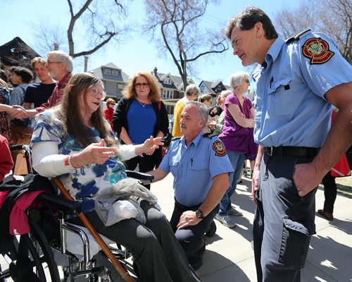 JASON HALSTEAD / WINNIPEG FREE PRESS  Helen Procner, who was pulled out of a fire in her Maryland Street home on April 23 with sister Neda Procner, speaks to Winnipeg Fire Department Cpt. Rob Labossiere (second right) and Lt. Rob Campbell at a barbecue held for the two at Westminster United Church in Wolseley on April 30, 2016. Both firefighters worked at the scene of the blaze.