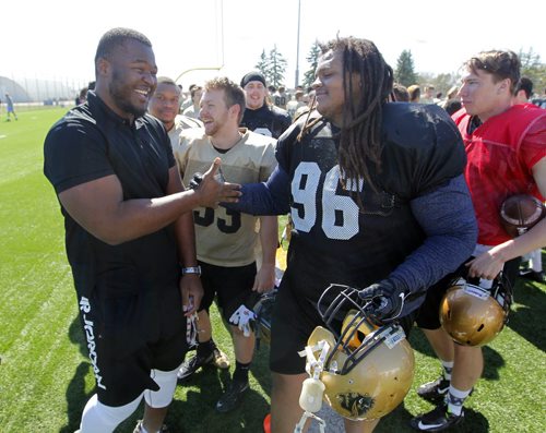 BORIS MINKEVICH / WINNIPEG FREE PRESS Bison football defensive lineman David Onyemata, left, after his selection in the NFL Draft. He was celebrated by all the Bison Football players after practice today at the University of Manitoba turf field. #96 is Tristan Bredin. April 30, 2016