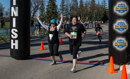 MIKE DEAL / WINNIPEG FREE PRESS Ainsley Read (left) raises her hands as she crosses the finish line with her friend Jennifer Dare completing the 5K race Sunday morning. Participants in the 12th annual Winnipeg Police Half Marathon, 2-person relay and 5K race raising money for the Canadian Cancer Society in support of brain cancer research. 160501 - Sunday, May 01, 2016