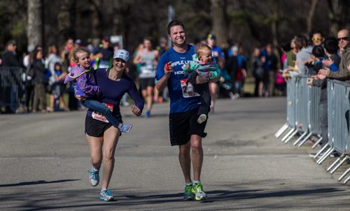 MIKE DEAL / WINNIPEG FREE PRESS Drew Dear and Courtney St. Croix carry their children Jordyn, 2, and Paityn, 4, across the finish line in the Police 2-person relay Sunday morning. Participants in the 12th annual Winnipeg Police Half Marathon, 2-person relay and 5K race raising money for the Canadian Cancer Society in support of brain cancer research. 160501 - Sunday, May 01, 2016