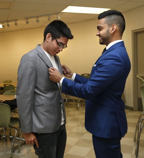 WAYNE GLOWACKI / WINNIPEG FREE PRESS     At right, Sandeep Singh, a sales representative with EPH Apparel checks the fit of a suit jacket on grade 12 Children of the Earth High School student  Kashtin Mekish. A retired businessman helped find a menswear store which has agreed to outfit about 17 male high school grads with suits, ties and shirts for their graduation and prom. Kevin Rollason  story.     May 4  2016