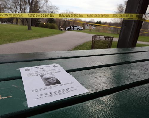 JASON HALSTEAD / WINNIPEG FREE PRESS  A poster for missing person Catherine Curtis remained on a bench as police and Medical Examiners staff work on the bank of Sturgeon Creek near the intersection of Booth Drive and Portage Avenue where a body was found in the afternoon of May 4, 2016.