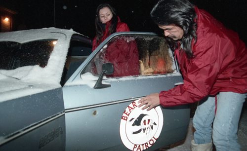 KEN GIGLIOTTI / WINNIPEG FREE PRESS FILES Brian McLeod and wife Sharon putting the Bear Clan's logo on their car before heading out on the Friday and Saturday night patrols in north end. 921218 - December 18, 1992