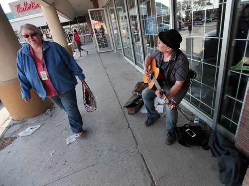 PHIL HOSSACK / WINNIPEG FREE PRESS - Tim (last name refused) thanks a contributor who threw a couple of bucks into his guitar case as he busks out front of the Manitoba Liquor store at Marion and St Mary's Road Friday afternoon. Tim Busks 3 times a week after working his day job and doesn't beleive buskers need lisencing. See story. May 6, 2016