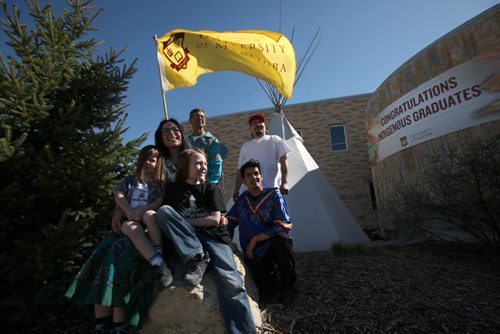 RUTH BONNEVILLE / WINNIPEG FREE PRESS  A group of organizers and committee members for this year's  27th Annual Traditional Graduation Pow Wow honouring U of M indigenous graduates gather near Investors Group Athletic Centre prior to event Saturday.  Names - Kristin Flattery with her kids Jordan (4yrs) and Gavin (10yrs), Marcel French (flag), Dwayne Berens (white shirt) and Waylon Flett (blue shirt).    May 07, , 2016