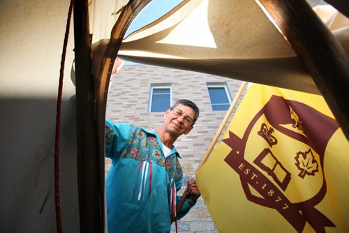 RUTH BONNEVILLE / WINNIPEG FREE PRESS  Marcel French one of the organizers for this year's  27th Annual Traditional Graduation Pow Wow honouring U of M indigenous graduates is proud of this years grads as he holds a U of M flag a opening of teepee near Investors Group Athletic Centre prior to event Saturday.   May 07, , 2016