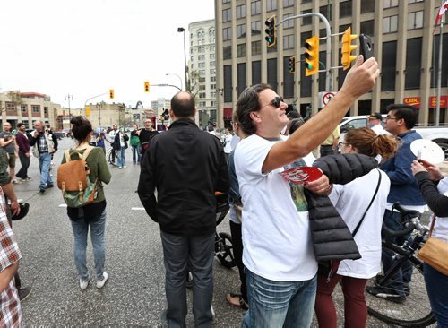 MIKE DEAL / WINNIPEG FREE PRESS  Stefano Grande Executive Director of the Downtown Biz takes a photo while taking part in this years Jane's Walk that took participants through the intersection of Portage Avenue and Main Street which has been closed off to pedestrian traffic since the late '70s. Some of the walkers carry masks which depict Jane Jacob's face and is meant to symbolize taking the opportunity to look at the city through the "lens" of Jane's perspective.   160508 Sunday, May 08, 2016
