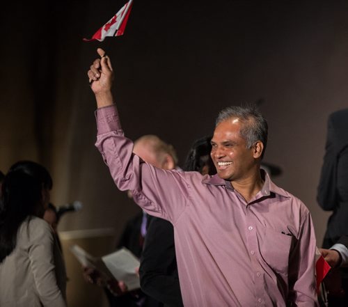 MIKE DEAL / WINNIPEG FREE PRESS New Canadian Anselm Abraham waves his flag after the citizenship ceremony at the Canadian Museum for Human Rights Monday afternoon. 160509 - Monday, May 09, 2016