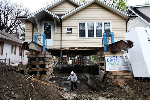 RUTH BONNEVILLE / WINNIPEG FREE PRESS  Farrell Lacquette a worker with Blue Maxx foundations and builders, is dwarfed in size by the house that stands on stilts around him as he works with the rest of his crew to pour a new foundation under a home at 250 Beaverbrook. Standup photo   May 10, , 2016