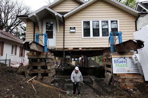 RUTH BONNEVILLE / WINNIPEG FREE PRESS  Farrell Lacquette a worker with Blue Maxx foundations and builders, is dwarfed in size by the house that stands on stilts around him as he works with the rest of his crew to pour a new foundation under a home at 250 Beaverbrook. Standup photo   May 10, , 2016